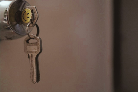 Auf dem Foto sieht man einen Wohnungsschlüssel mit Smiley in einem Schloss, zusätzlich hängen zwei weitere Schlüssel am Schlüsselring.